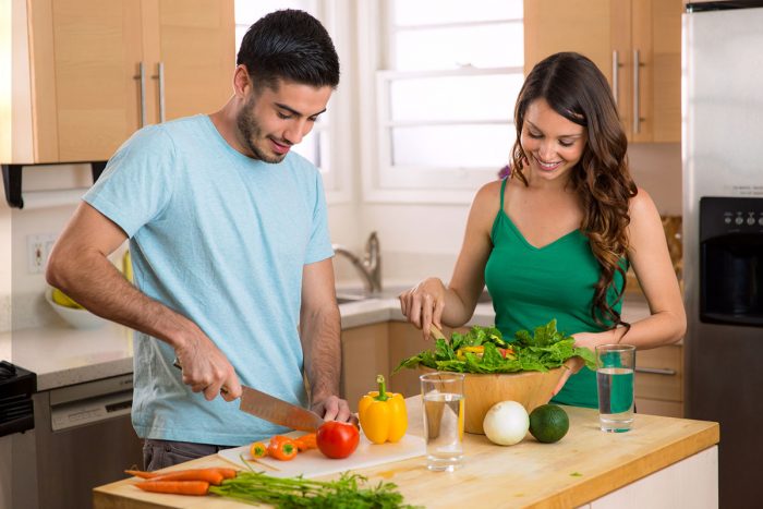 Attractive man and woman prepping low calorie dinner in kitchen